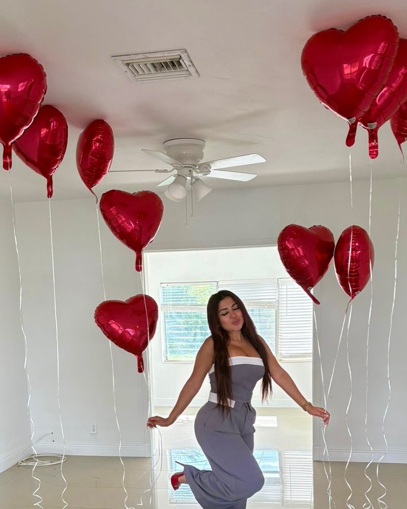 Cindy dancing under red heart balloons